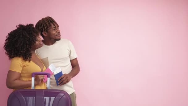 离境资料 奇怪的夫妇 广告背景 快乐的黑人男人和女人摆出一副带着粉红行李箱票的样子 — 图库视频影像