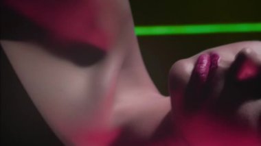 Vertical video. 90s beauty. Fashion model. 2000s look. Cropped portrait of teen girl face posing in red green color neon flash light on black.