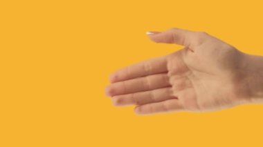 Vertical video. Goodbye gesture. Farewell sign. See you later. Female hand waving bye isolated on orange copy space background.