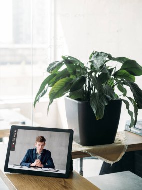 İnternetteki konferans. Görüntülü konuşma. Sanal toplantı. Dijital ofis işyerindeki tablet ekranda kendine güvenen iş adamı.