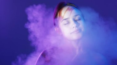 Huzur büyüsü. Huzurlu bir kadın. Çifte portre. Mutlu şehvetli kadın mavi arka plan gölgesi yansıması mor beyaz duman üfleme bulanıklığı.