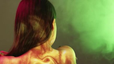 İyileştirme tedavisi. Dişi cilt bakımı. Çifte portre. Pürüzsüz tene dokunan zarif arka plan görüşlü kadın. Neon ışıklı dumanlı arka plan yansıması. Görüntü bulanıklığı..