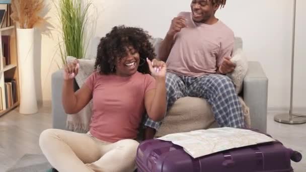 度假的兴奋 一对快乐的夫妇浪漫的旅行 兴高采烈的黑人男女坐在拥挤的行李箱里跳舞 画着灯光室内部慢动作的地图 — 图库视频影像