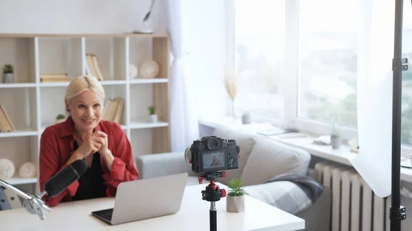 コンテンツ作成者Vlogストリーム ソーシャルメディアのコミュニケーション シニアインフルエンサー女性話すビデオ上のカメラの三脚に焦点を当てたライトホームインテリアとともにフリースペース — ストック写真