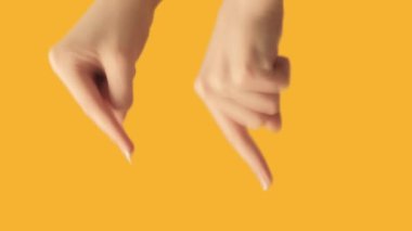 Vertical video. Hand pointing. Previous page. Demonstrating gesture. Female fingers showing something on orange free space background.