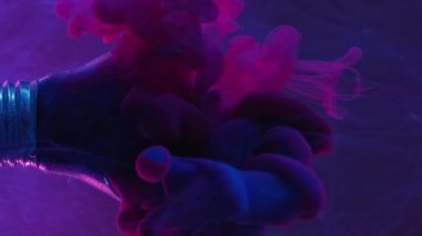 Vertical video. Paint splash. Lamp explosion. Blue pink color vapor cloud motion in broken glass light bulb in water on dark purple abstract background.