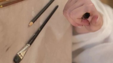 Vertical video. Painting tools. Art supplies. Creative workplace. Closeup of professional female artist hand choosing paintbrush from set on table.
