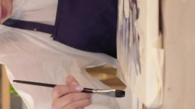 Vertical video. Painting art. Creative process. Hobby inspiration. Unrecognizable artist woman creating watercolor artwork with paintbrush on canvas.