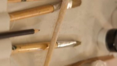 Vertical video. Art supplies. Painting workplace. Closeup of acrylic gouache paint bottles palette still life picture canvas paintbrush tools set organizer.