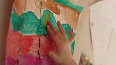 Vertical video. Child art. Finger painting. Kid inspiration. Creative hobby. Little girl artist hand creating abstract colorful artwork.