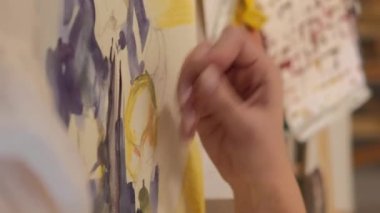 Vertical video. Painting art. Creative process. Talent imagination. Female artist hand creating yellow blue abstract artwork with wax crayon watercolor on canvas.