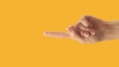 Vertical video. Advertising gesture. Special offer. Female hand finger pointing up at bright orange copy space commercial background.