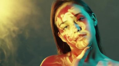 İyileştirme tedavisi. Şehvetli bir kadın. Çifte portre. Zarif bir kadın pürüzsüz tene dokunuyor. Neon ışığı yanıp sönen arka plan. Dumanlı yansıma kalıbı..