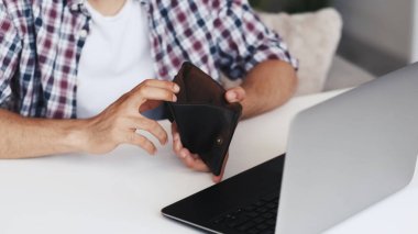 İnternet dolandırıcılığı. Çevrimiçi dolandırıcılık. Serbest çalışma riski. Beş parasız zavallı adamın elleri iş yerindeki boş cüzdanı dizüstü bilgisayarla gösteriyor..