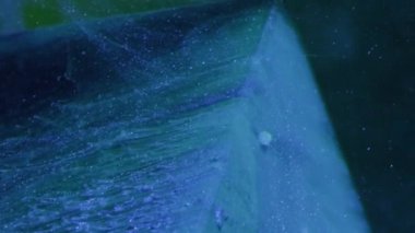 Vertical video. Glitter splash. Ink water. Snow cascade. Blue color paint smoke flow motion over ice cube angle on dark abstract background.