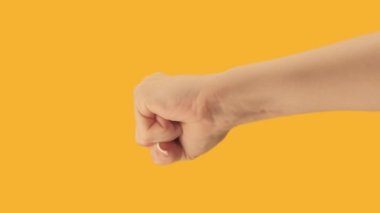 Vertical video. Protest fist. Strike demonstration. Female activist clenched hand knocking anger gesture on orange copy space background loop.