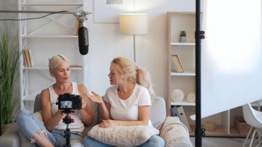 Video blogu. Ev röportajı. Blogger iletişimi. İki rahat kadın, modern ekipmanlı ev stüdyosunda kameranın önünde içeriği kaydediyor..