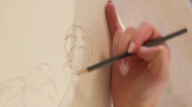 Vertical video. Artwork drawing. Creative process. Painting art. Closeup of female artist hand sketching line with pencil on canvas.