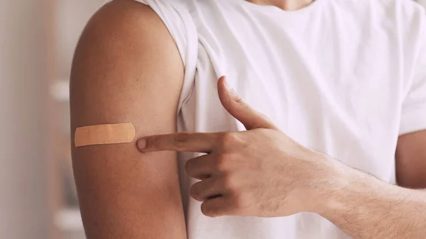 Flu vaccination. Inoculation shot. Effective virus immunization. Unrecognizable male patient showing adhesive bandage on arm shoulder.