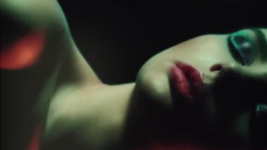 Vertical video. Retro beauty. 90s fashion. Disco night. Closeup of relaxed teen girl model face with artistic makeup closed eyes posing in red green color neon flash light on dark.