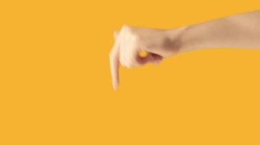 Vertical video. Finger pointing. Previous page. Recommending gesture. Female hand sign recommending something before on orange empty space background.