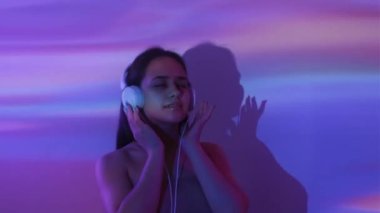 İyileştirici müzik. Sakin bir kadın. Çifte portre. Kulaklıklı siluet kadın harmoni hissediyor rengarenk ışık desenleri arka planda dans ediyor.