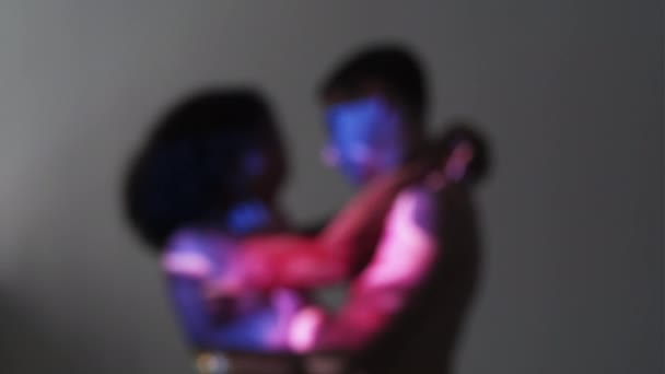 爱的感情 模糊的夫妇 双曝光肖像 色彩艳丽的男人和女人在灰色背景下拥抱在一起 紫色蓝色霓虹灯闪烁着光芒 — 图库视频影像