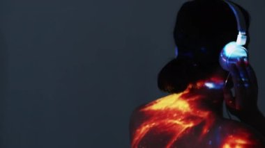 Müzik ilhamı. Çifte teşhirci kadın. Sakin bir zihin. Kulaklıklı kadın portresi galaksinin parlak ışıklarında gri pozlar vererek arka plan fotokopi alanını örtüyor.