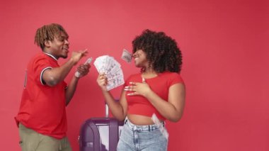 Zengin tatil. Mutlu bir çift. Yolculuk heyecanı. Neşeli siyah adam para dolu banknotlar saçıyor. Yanında bir kadınla poz veriyor. Kırmızı arka plan..