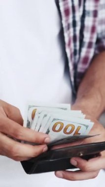Dikey video. Tasarruf. Finansal gelir. Zenginlik başarısı. Tanınmayacak kadar zengin bir adam cüzdanından 100 dolar para sayıyor..