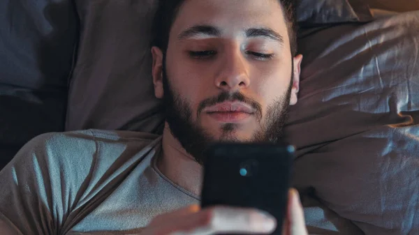 インターネット不眠症 夜をオンラインで 携帯中毒だ 退屈眠いです疲れました男使用して電話スクロールフィードでベッドの後半でダークベッドルーム — ストック写真