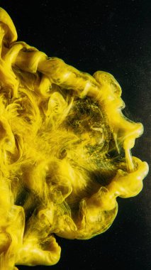 Boya sıçraması. Mürekkep suyu. Akışkan puf. Fantezi bulanıklığı. Parlak simli desen üzerinde sarı renk buhar bulutu koyu siyah soyut arkaplan.