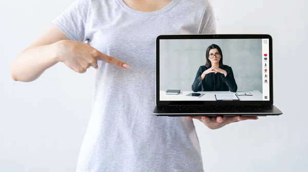 Business webinar. Video meeting. Digital conference. Woman pointing at confident female coach online on laptop screen isolated on neutral white.