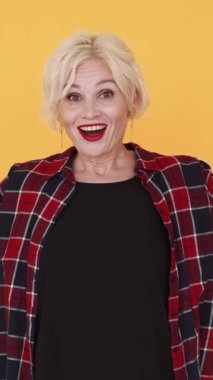 Dikey video. Saklambaç oyunu. Mutlu kadın. Orta yaşlı, etkileyici bir kadın. Gözleri görüyor ve sarıya bürünmüş sevinçle bakıyor..