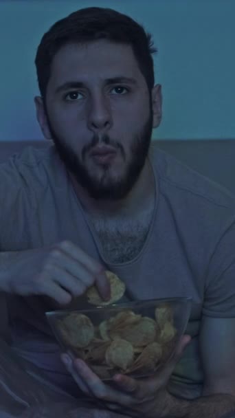 영상입니다 휴식을 남자가 어두운 방에서 파란깜박거리는 불빛으로 감자튀김을 — 비디오