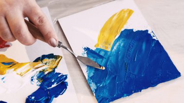 Soyut resim. Boyama işlemi. Yaratıcı stüdyo. Tuvale spatula ve mavi sarı boyalarla resim çizen tanınmayan bir kadın..