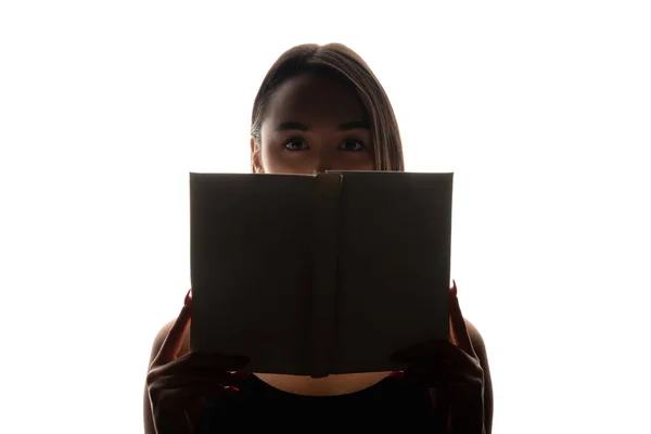 阅读谜语 学生的恐惧 考试焦虑 黑色背光的恐怖女性眼睛轮廓 隐藏在打开的书后面 背景是白色的复制空间 — 图库照片