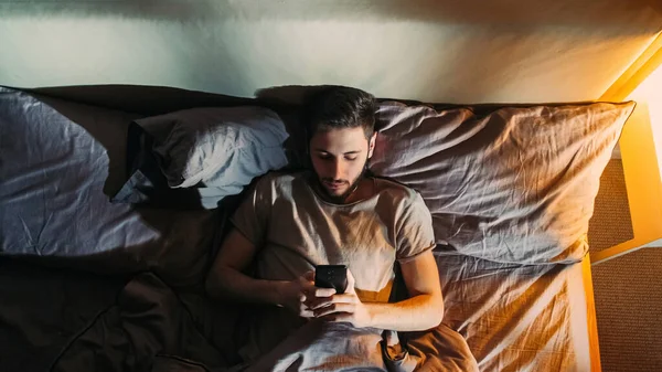電話の夜 オンライン不眠症 後期仮想通信 退屈眠い落ち込んで男サーフィンインターネット使用して電子ガジェットでベッドでダークホームベッドルーム — ストック写真