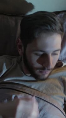 Dikey video. Gece endişesi. Uyku bozukluğu. Panik atak. Korkmuş bir adam, karanlık bir yatak odasında kâbusla uyanır..