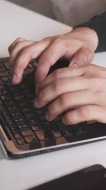Dikey video. Uzaktan kumanda. Serbest bir iş. Bilgisayar teknolojisi. İş yerindeki not defterine akıllı telefon dijital cihazıyla yazı yazan erkeklerin yakın plan görüntüleri..