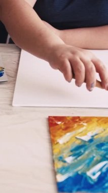 Dikey video. Sanat eseri yaratımı. Kadın ressam. Soyut resim. Tuvale spatula ve mavi boyayla resim yapan tanınmayan bir kadın..