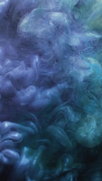 垂直ビデオ 流体のスプラッシュ インクの水 ペンキを塗るんだ 水中爆発だ 青い紫色の煙雲のフレアの輝き塵の浮遊運動の抽象的な背景を明らかに — ストック動画