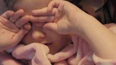 Dikey video. Yorgun çocuk gece uykusu. Çocuk yatma vakti. Yorgun, pijamalı, gözlerini ovuşturan, rahat bir yatakta uyuyan küçük bir kız..