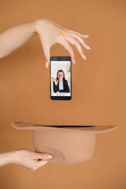 E-öğrenme bilgisi. Mesafe çalışması. Video konferansı. Dijital eğitim. Tatmin olmuş internet öğretmeniyle telefonu düşüren kadın kahverengi şapkaya bürünüyor..