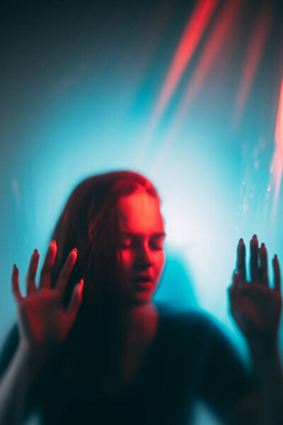 Woman crisis. Mental disorder. Red blue color light defocused exhausted desperate female silhouette trapped behind transparent wall.