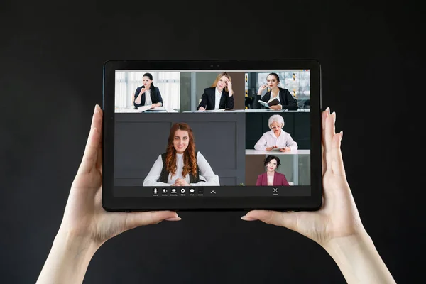 Video call. Business meeting. Distant cooperation. Professional female team brainstorming working online on tablet screen in hands on black.