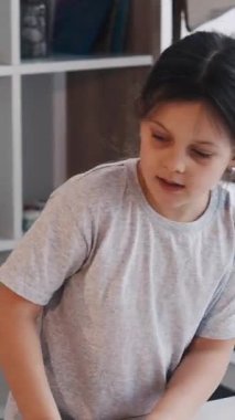 Dikey video. Sanatsal hobi. Yaratıcı kız. Resim okulunda. Dişi çocuk, hafif stüdyo içinde beyaz kağıda kalemle çizmeye başlıyor..