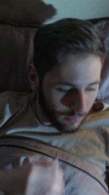 Dikey video. Gece endişesi. Uyku bozukluğu. Panik atak. Korkmuş bir adam, karanlık bir yatak odasında kâbusla uyanır..