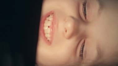 Dikey video. Çocuk filmi. Geç vakit eğlencesi. Çocuk oyuncağı. Gülümseyen mutlu küçük kız telefonda animasyon film izlerken eğlendi..