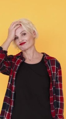 Dikey video. Yüz jesti. Kafası karışık bir kadın. Anlamsız bir durum. Utanmış kadın yüzünü ellerle kapatıyor. Destansı sarı poda başarısız oluyor..